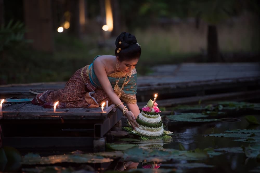 A traditionally dressed woman releasing a krathong